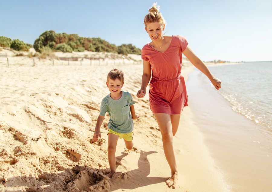 A photo of a woman and her son running along the beach.