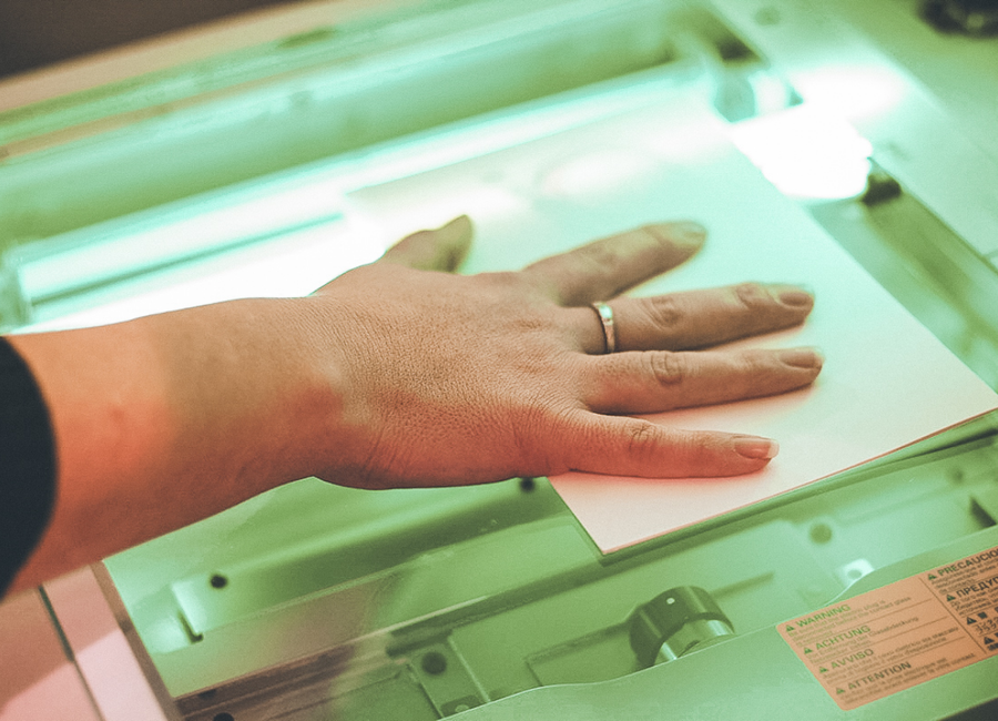 A woman’s hand placing a photo face-down on a scanner.