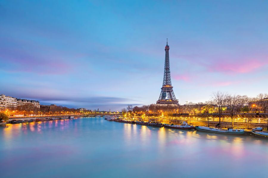 A photo of the Eiffel Tower taken across the river at dusk