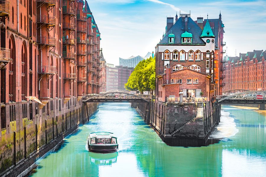 A boat on the river in between two buildings, where two forks of the water meet.